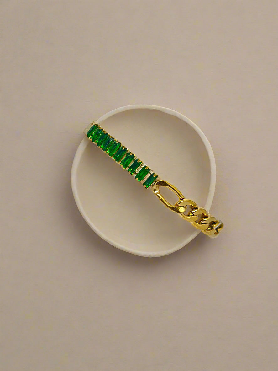 Gold bracelet with green stones on a white surface